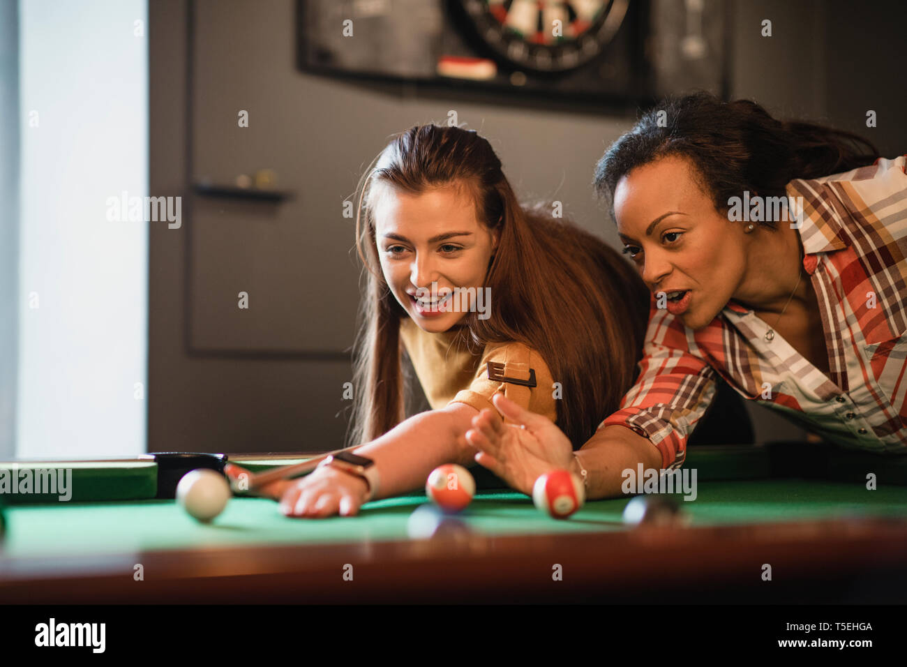 Close-up von zwei weiblichen Freunde spielen eine Partie Pool. Sie sind Futter bis der Schuss und üben. Stockfoto