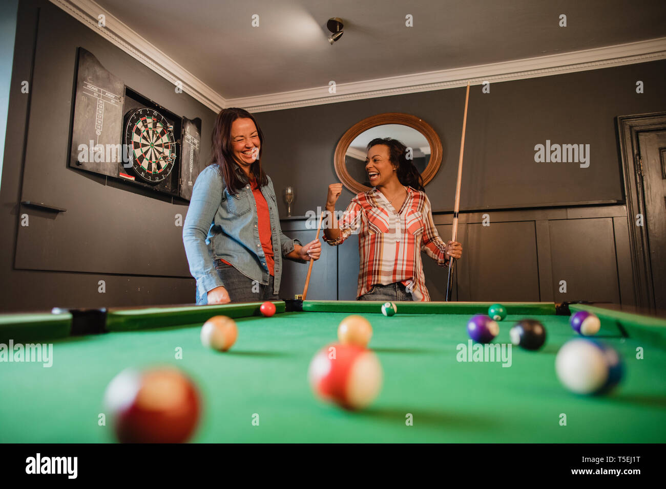 Zwei mittig nach Freunden ein Spiel der Pool in einem Spielzimmer in einem Haus. Stockfoto