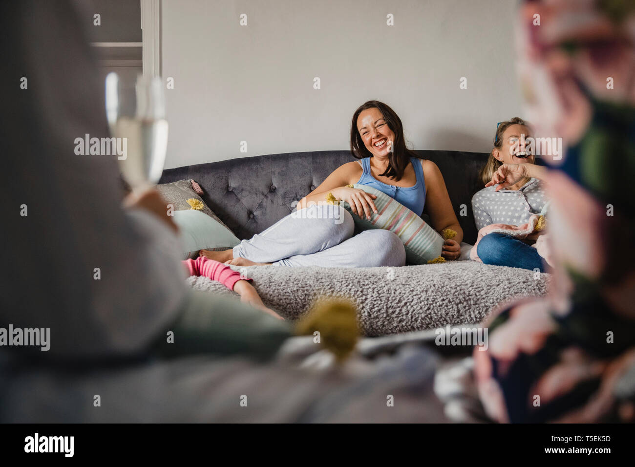 Mitte der erwachsenen Frau in ein Schlafzimmer, in ihrem Pyjama gekleidet, beim Sitzen auf einem Bett im Gespräch mit Ihren Freunden. Stockfoto