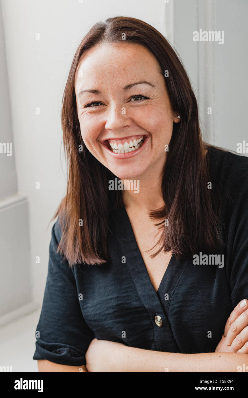 Porträt einer erwachsenen Frau in die Kamera schaut und lächelnd. Sie ist legere Kleidung. Stockfoto