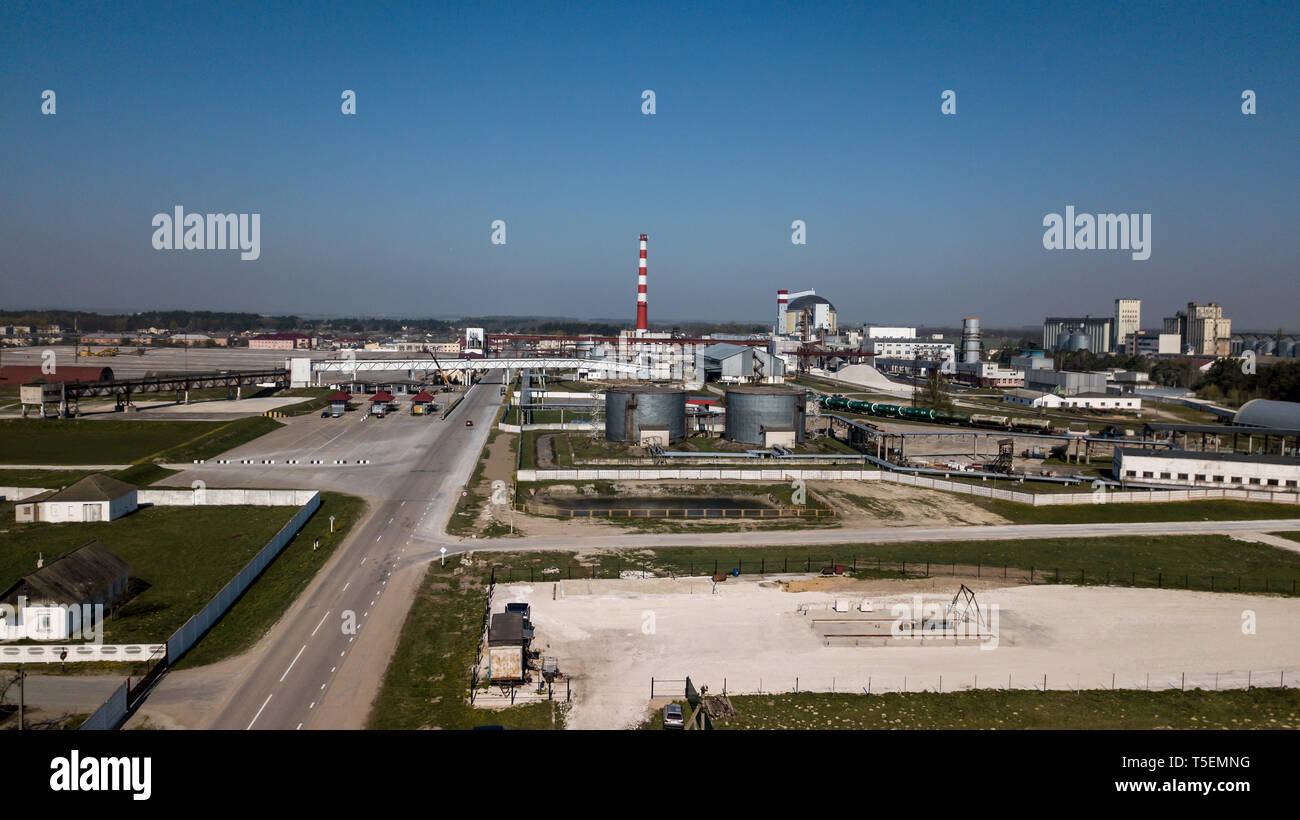 Eine riesige Ölraffinerie mit Metall Strukturen, Rohre und Destillation der Komplexe mit brennenden Lichtern in der Abenddämmerung. Luftaufnahme Stockfoto