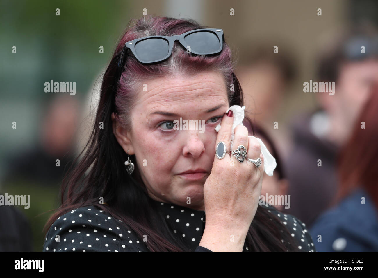 Ein Mitglied der Öffentlichkeit hört auf der Trauerfeier für ermordeten Journalisten Lyra McKee außerhalb St. Anne's Cathedral in Belfast. Stockfoto