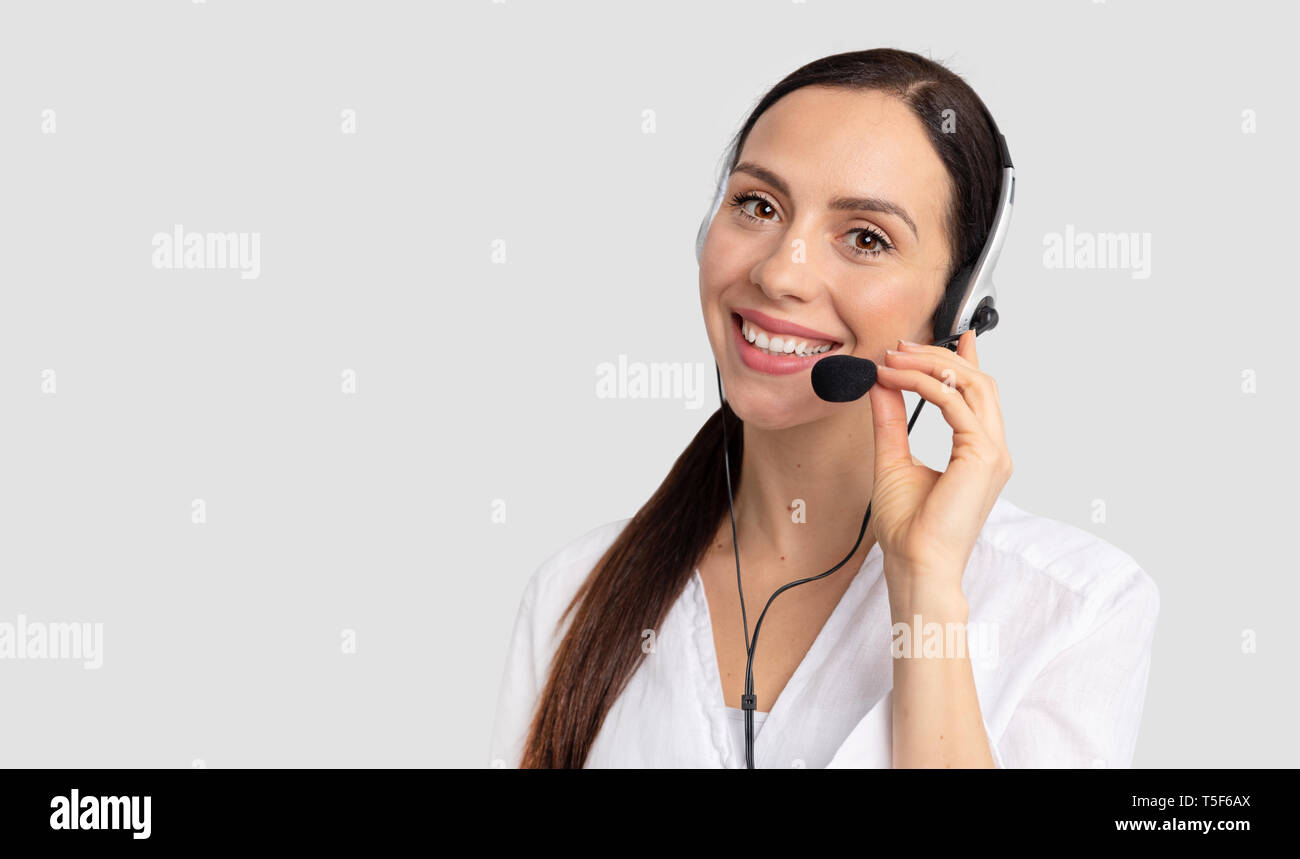 Berater von Call Center in Kopfhörer auf grauem Hintergrund. Helpline Operator mit Headset Stockfoto