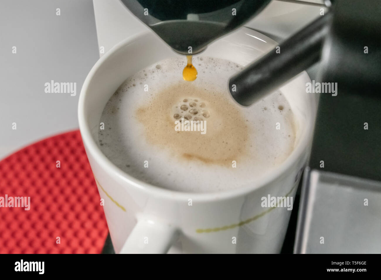 Die Cappuccino - Nahaufnahme von espresso Gießen aus der Kaffeemaschine. Cappuccino hat die wichtigsten Bestandteile sind Espresso, Milch. Unscharfer Hintergrund Stockfoto