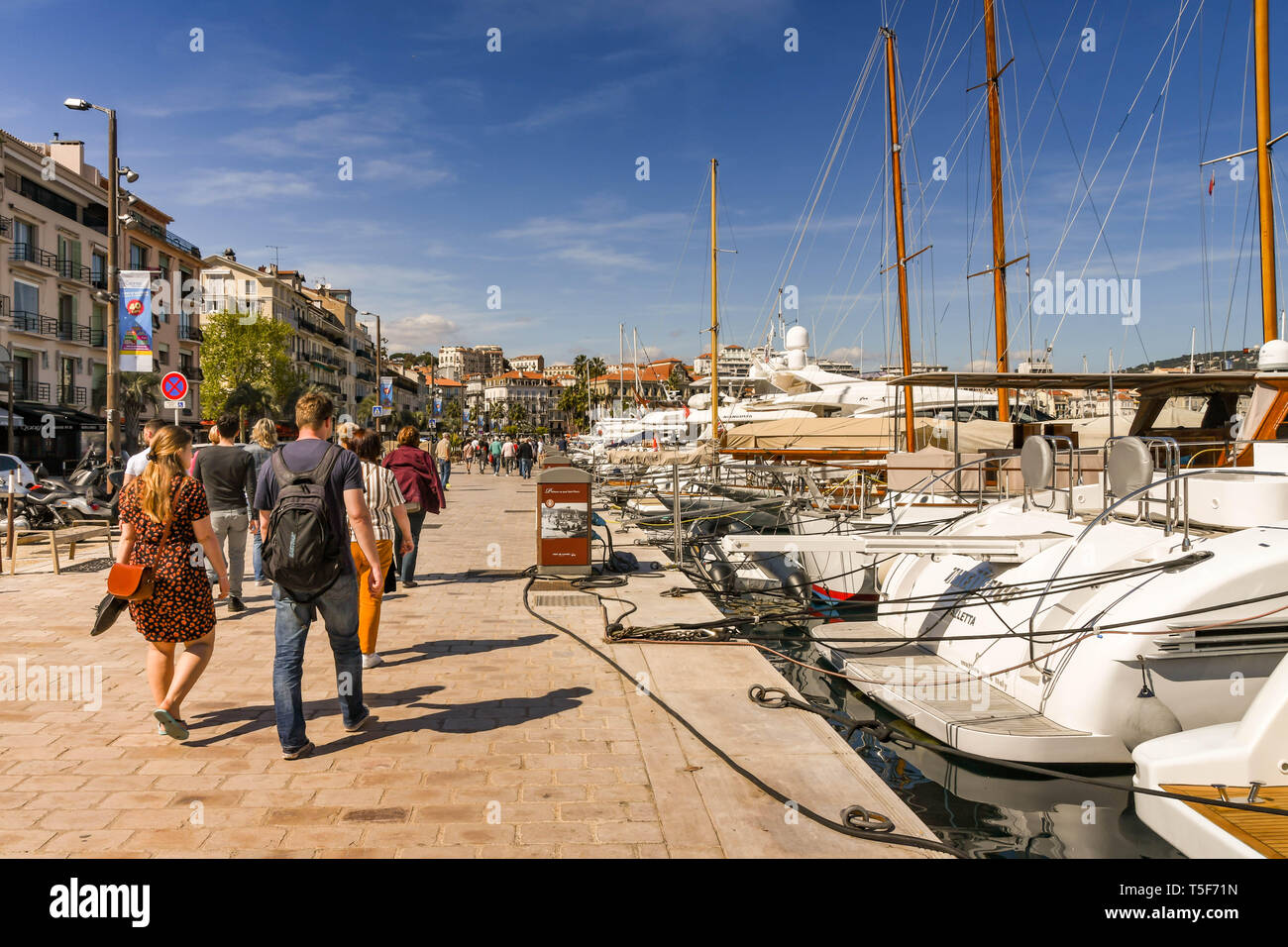 CANNES, Frankreich - April 2019: Menschen zu Fuß entlang der Hafenpromenade in Cannes. Stockfoto