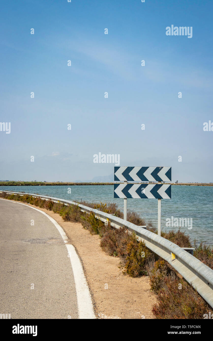 Double chevron Pfeile auf der Straße Zeichen vor Wasser links Stockfoto