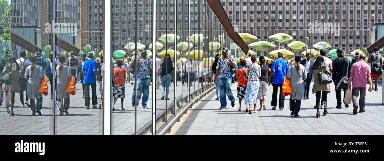 Reflexion der Gruppe der multikulturellen Menschen breite Fußgängerbrücke zu Fuß zum & vom Eingang Westfield Einkaufszentrum East London Stratford City Newham GROSSBRITANNIEN Stockfoto