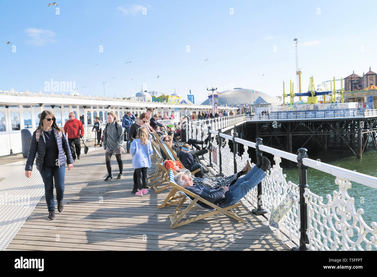 Die Menschen genießen das sonnige Wetter auf dem Boardwalk Palace Pier von Brighton, East Sussex, England, Großbritannien Stockfoto