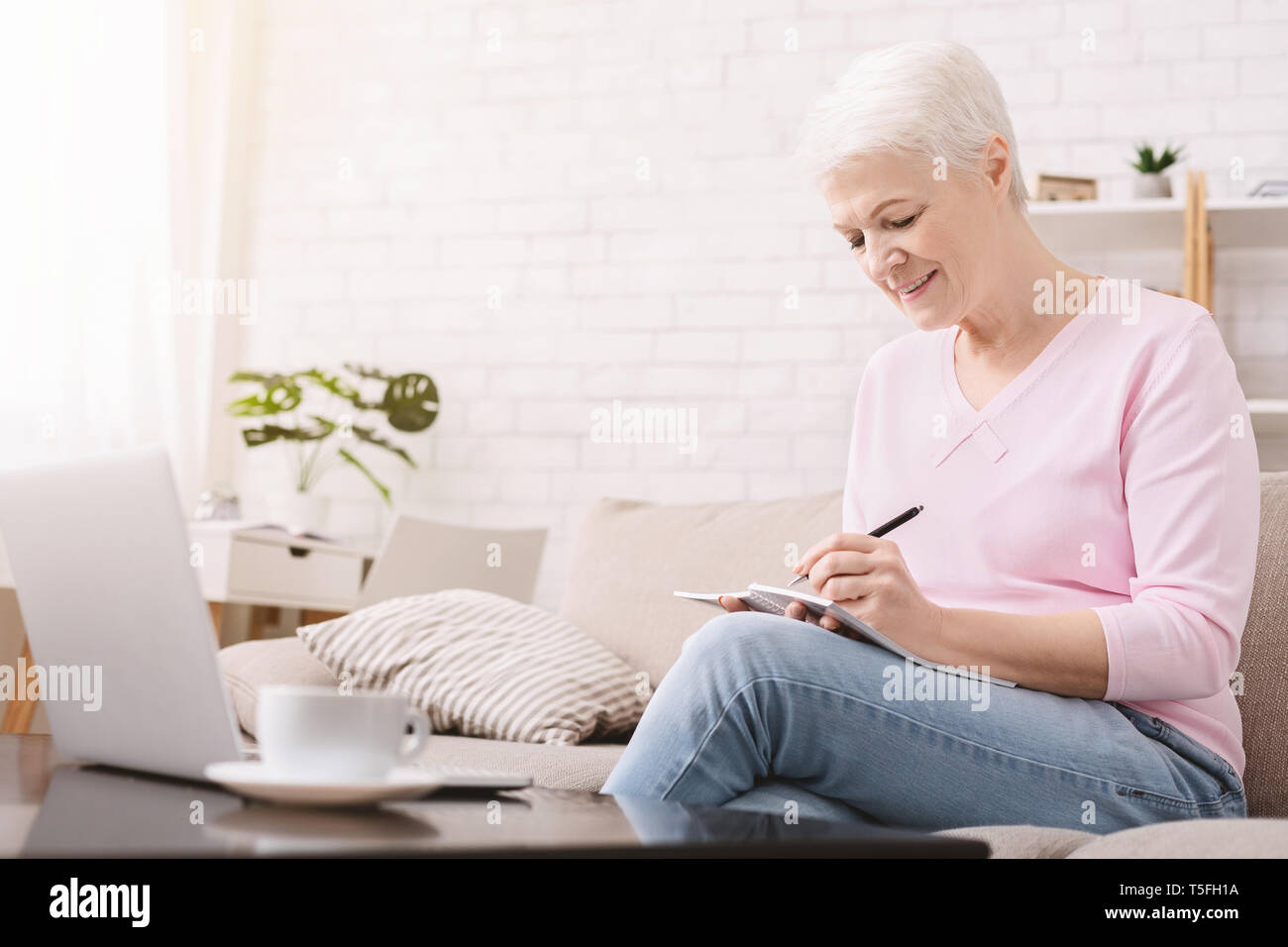 Ältere Frau schreiben sie Gedanken und Arbeiten am Laptop Stockfoto