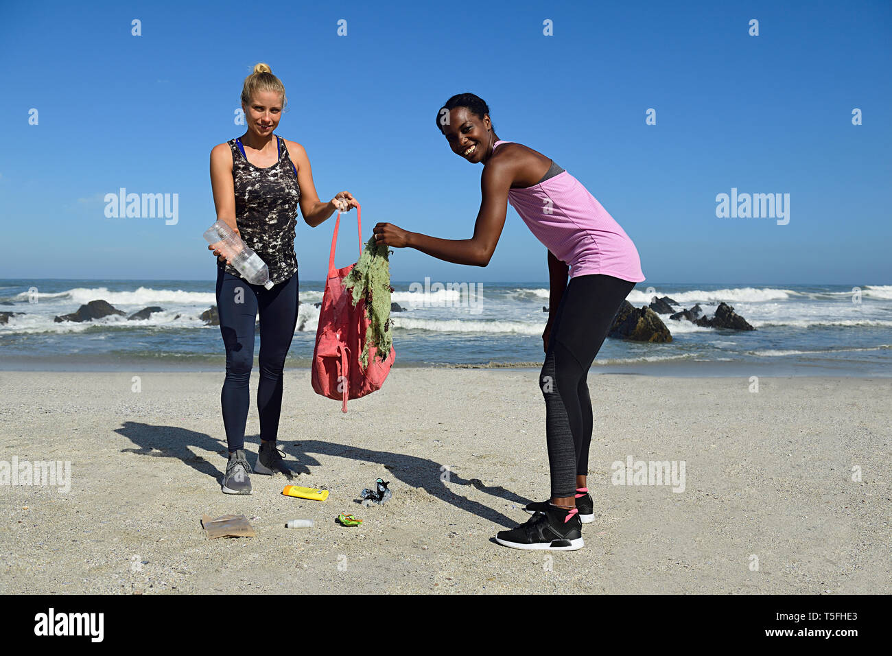 Portrait von zwei lächelnde Frauen Reinigung der Strand von Kunststoffabfällen Stockfoto