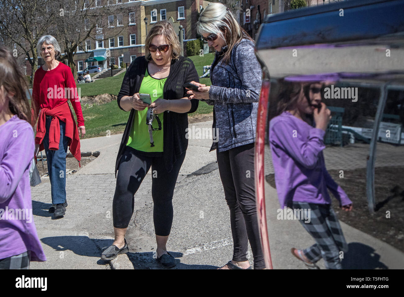 Zwei Frauen ihre Zelle Consult, ein Mädchen und ihre Silhouette spiegelt sich in der Farbe von einem geparkten Auto. Stockfoto