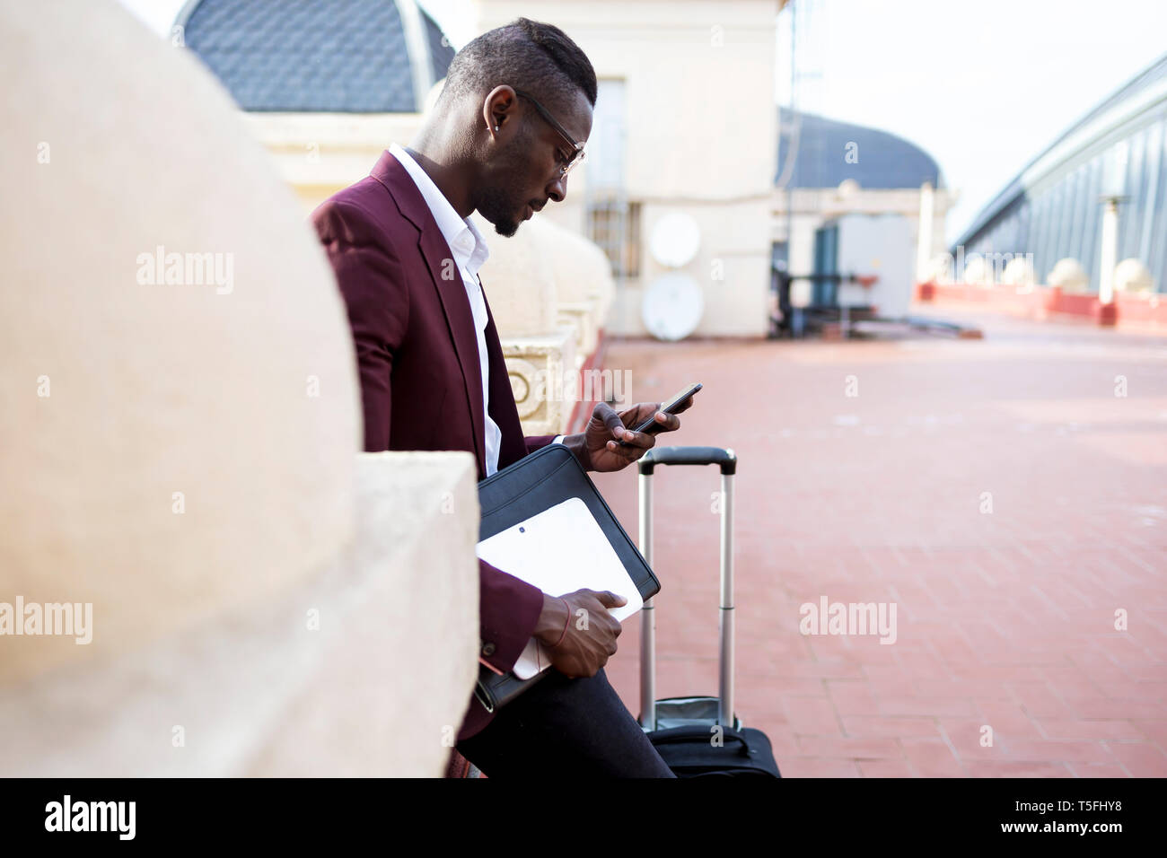 Junge entrepüreneur Warte auf der Hotel Terrasse für seine Ernennung mit Smartphone Stockfoto