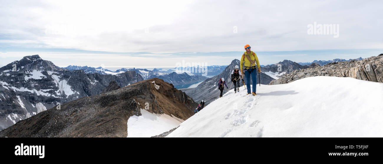 Grönland, Sermersooq, Kulusuk, Schweizerland Alpen, Gruppe von Menschen zu Fuß in der verschneiten Bergwelt Stockfoto