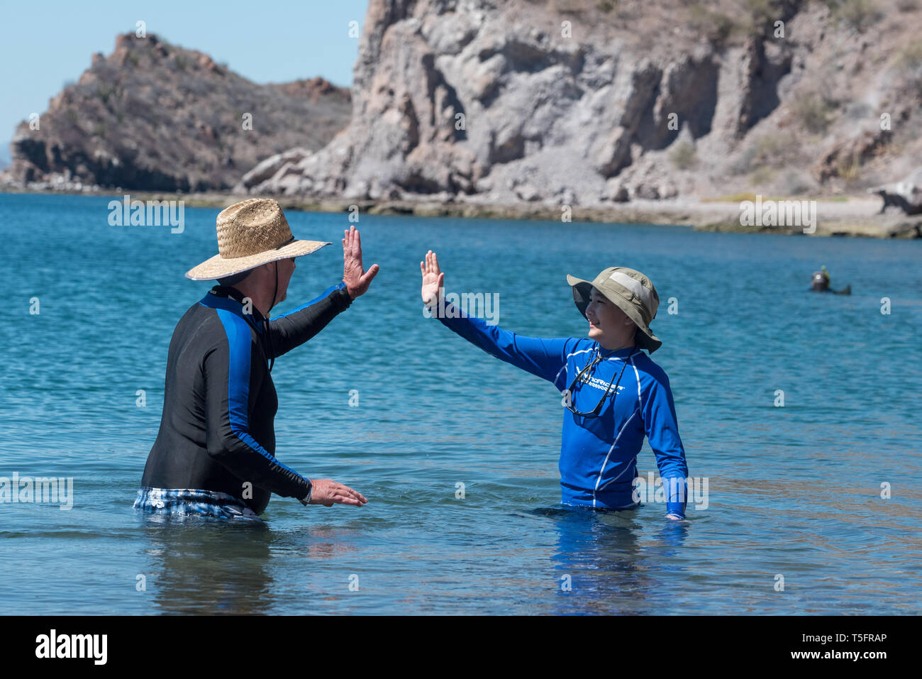 Mann und der Junge hohe Fiving, Bucht von Loreto Nat. Park, Baja California Sur, Mexiko. Stockfoto
