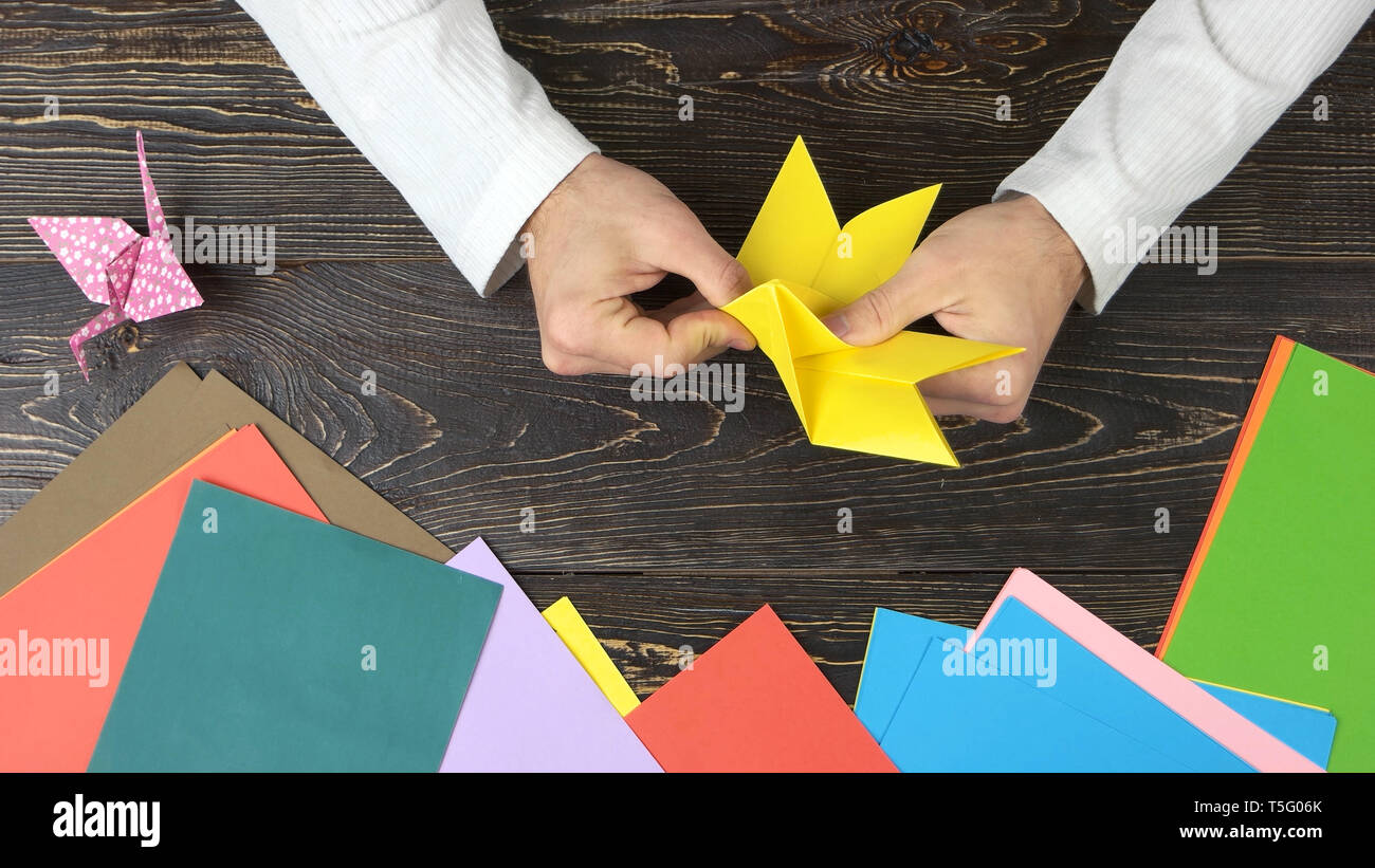 Männliche Hände falten gelbe Blatt Papier. Stockfoto