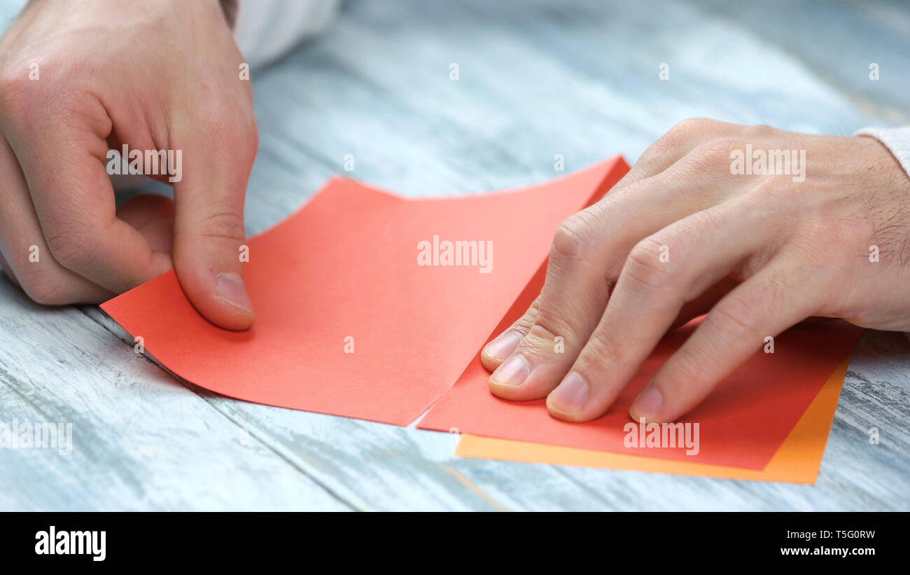 Mann Erstellen Origami mit rotem Papier hautnah. Stockfoto