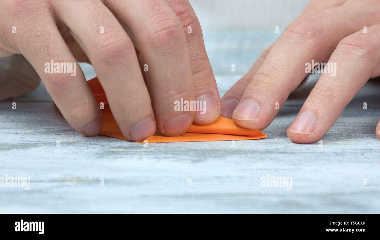 Close up männliche Hände falten orange Papier. Stockfoto