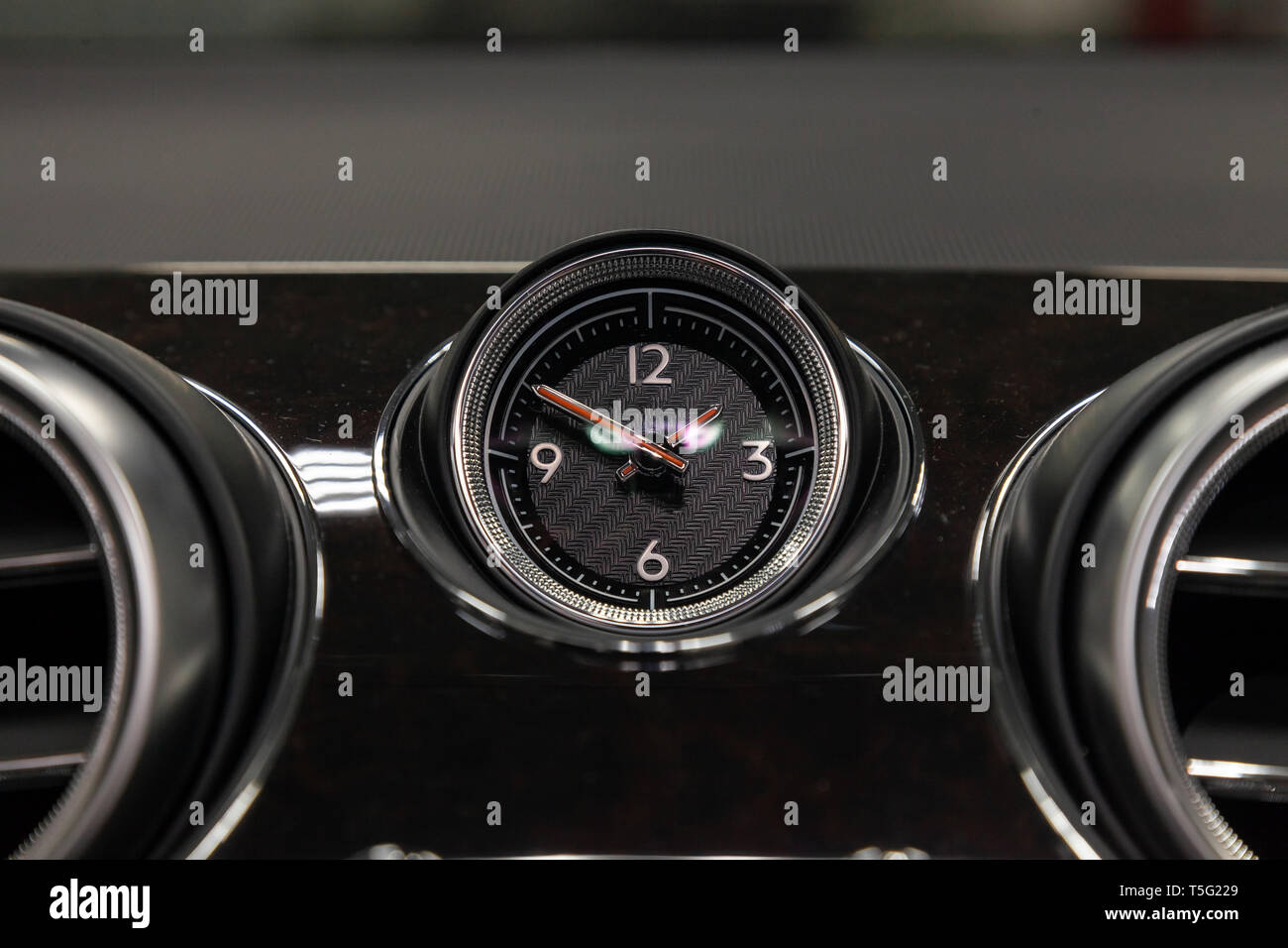 Die Uhr auf dem Armaturenbrett eines teuren Auto ist Close-up, mit  natürlichem Leder Schwarz und Braun woooden Verkleidung abgedeckt, ein  weißes Zifferblatt, ein roter Pfeil Stockfotografie - Alamy