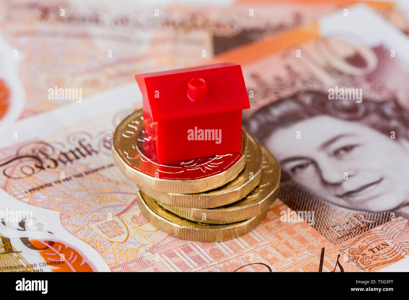 Britisches Englisch sterling Noten und Münzen mit einem Monopol rotes Haus auf der Oberseite. Eigenschaft Investition Konzept, ein Haus kaufen. Vereinigtes Königreich Stockfoto