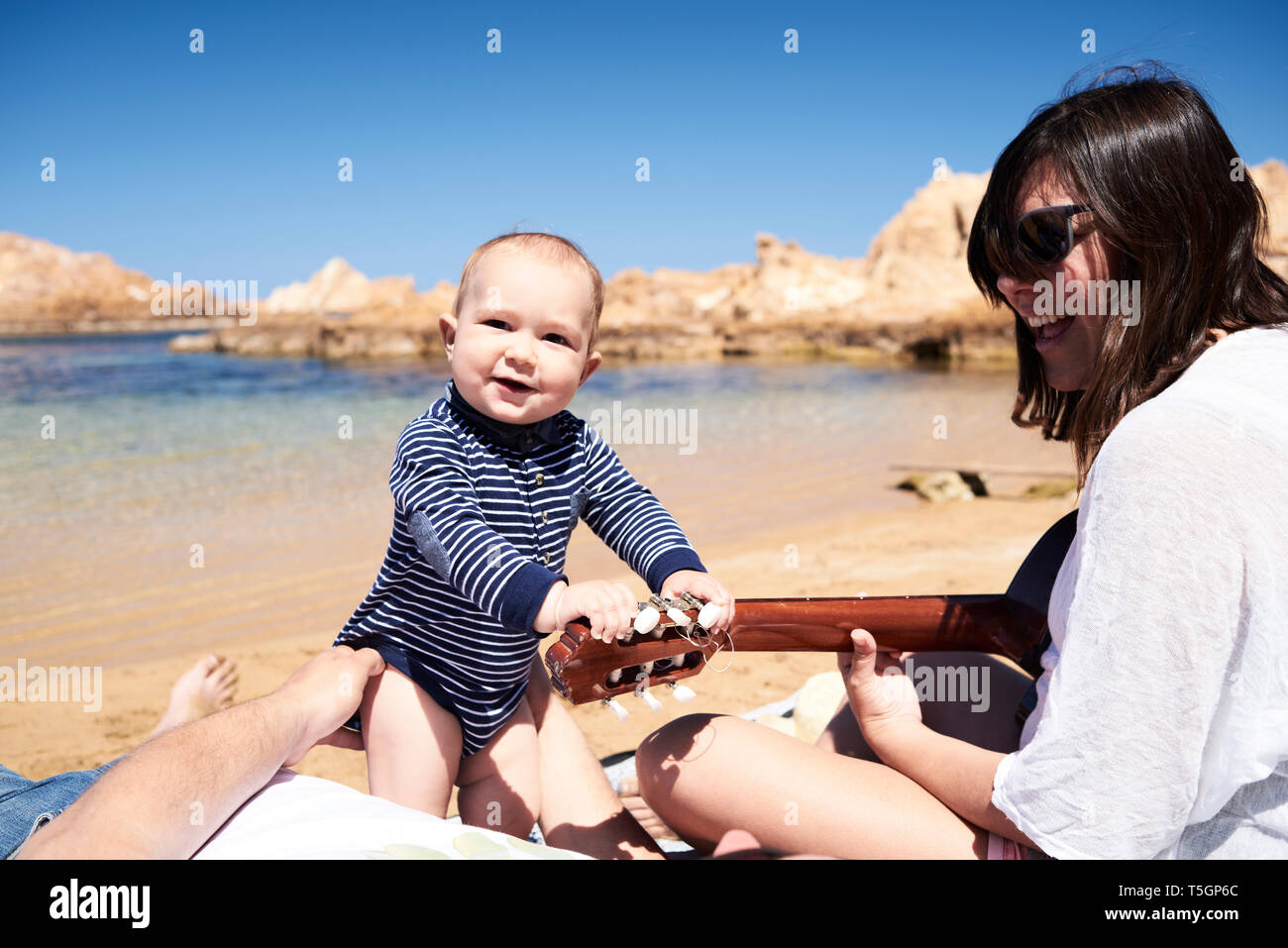 Spanien, Menorca, Portrait von lächelnden kleinen Jungen mit den Eltern am Strand Stockfoto