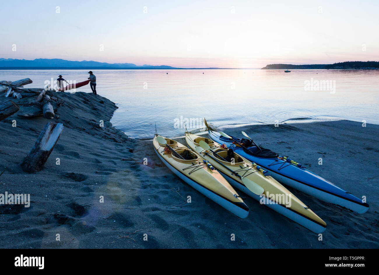 Menschen Männer Freunde Kajakfahren im Meer, die Boote am Strand bei Sonnenuntergang. Whidbey Island, Washington, United States Abenteuer im freien Wasser Sport reisen. Stockfoto