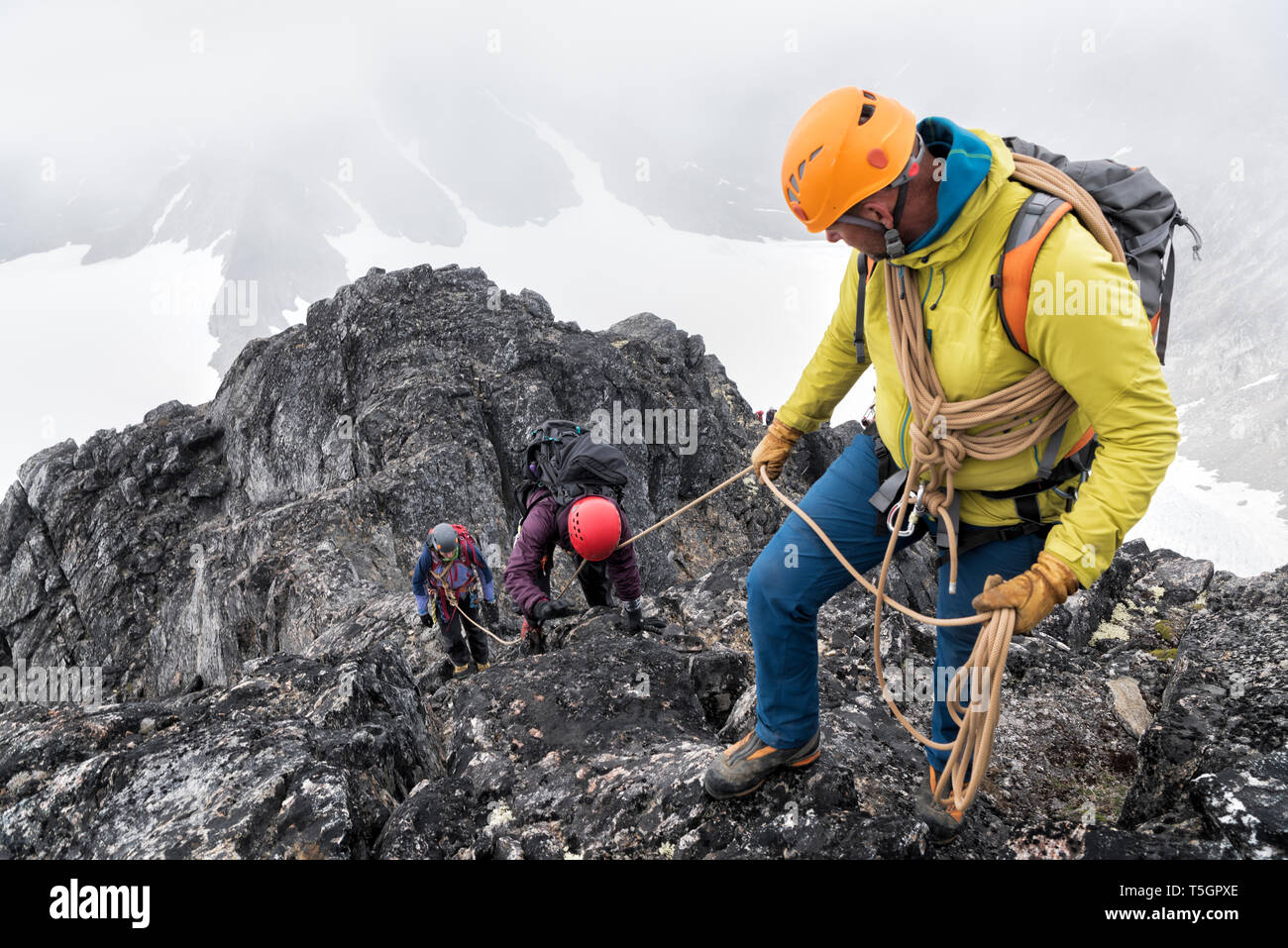 Grönland, Sermersooq, Kulusuk, Schweizerland Alpen, Bergsteiger mit Seil aufsteigend rocky mountain Stockfoto