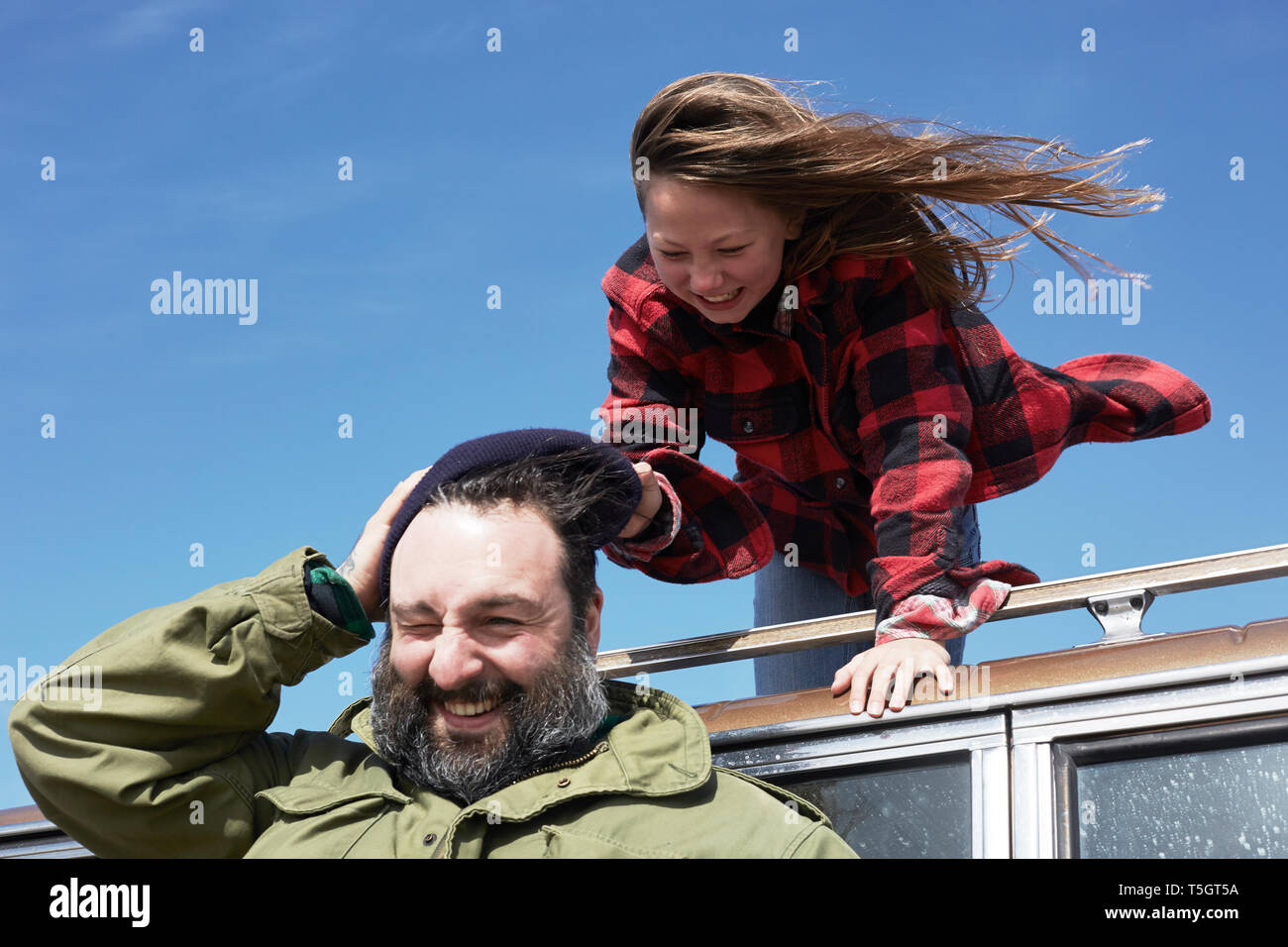 Verspielte Tochter ziehen Cap von Vaters Kopf Stockfoto