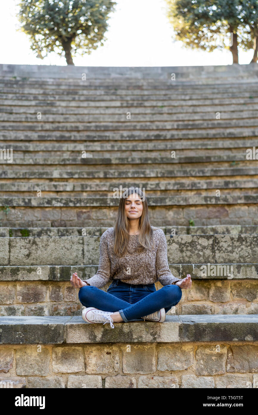 Junge Frau sitzt im Freien auf Treppen Yoga Stockfoto