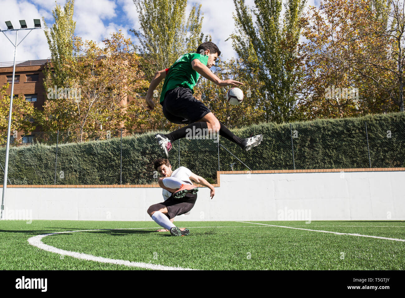 Bestimmt fußball Spieler kicken Kugel auf Feld overjumping Player auf dem Boden Stockfoto