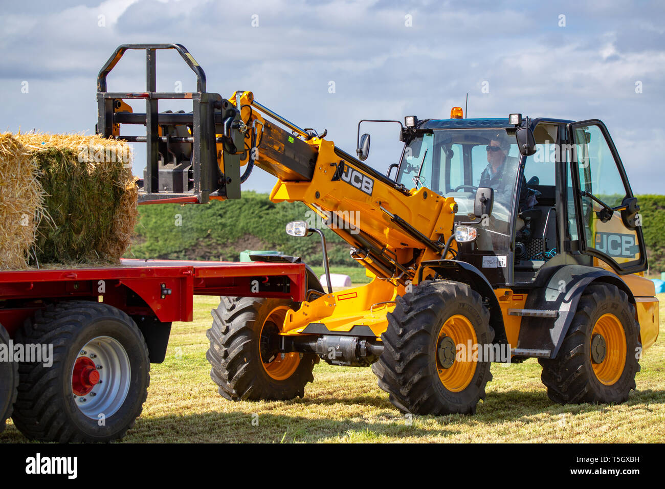 Kirwee, Canterbury, Neuseeland, 27. März 2019: der Landwirt wird veranschaulicht, wie die JCB Teleskoplader funktioniert so gut stapeln haybales auf der Südinsel Agri Stockfoto