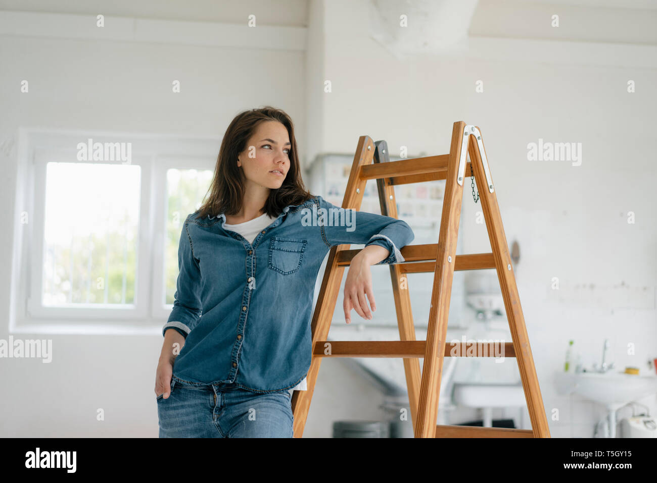 Hübsche Frau lehnte sich auf der Leiter Stockfoto