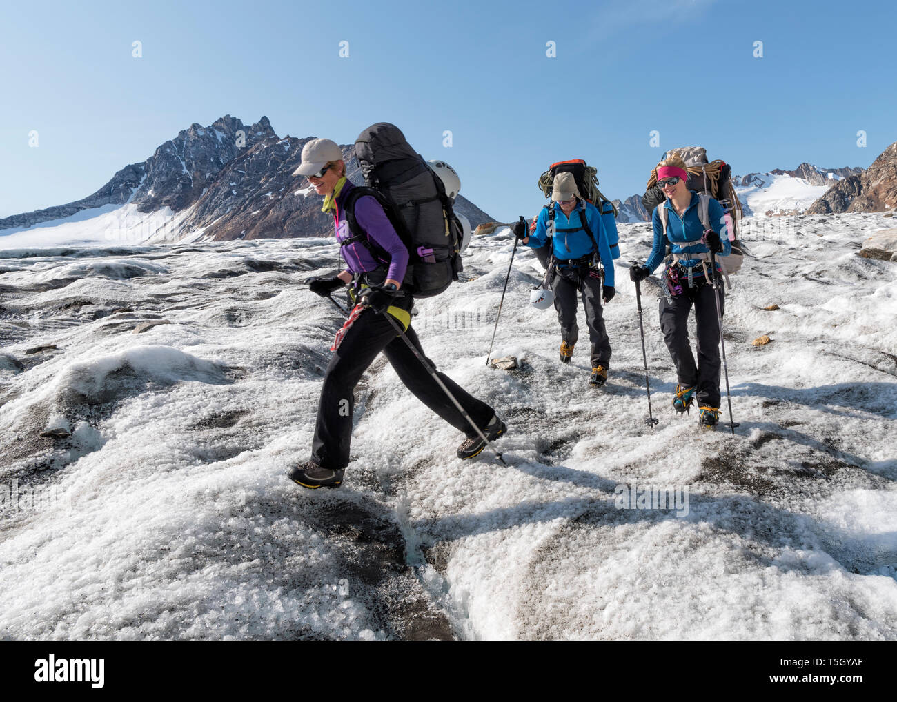 Grönland, Sermersooq, Kulusuk, Schweizerland Alpen, drei Leute, die in der verschneiten Bergwelt Stockfoto