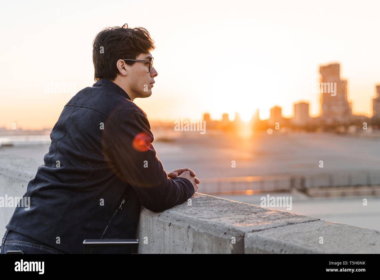 Spanien, Barcelona, Profil der junge Geschäftsmann lehnte sich an eine Wand bei Sonnenuntergang zu betrachten Stockfoto