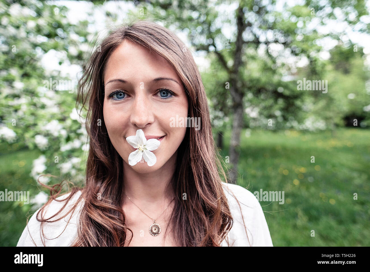 Portrait von lächelnden jungen Frau mit Apple Blossom in ihrem Munde. Stockfoto