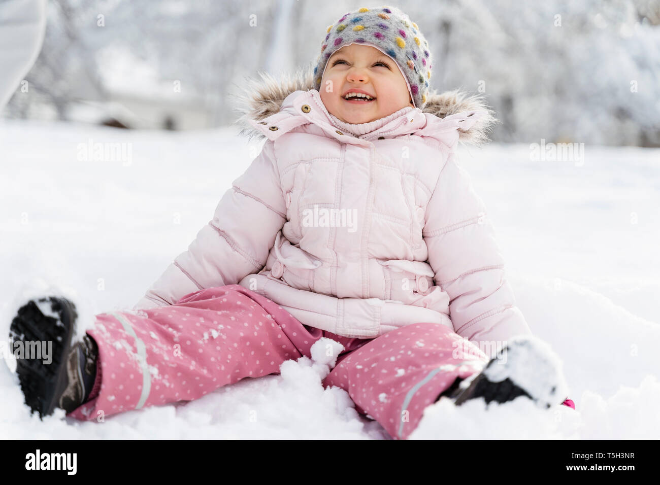 Süße kleine Mädchen sitzen im Schnee im Winter Stockfoto
