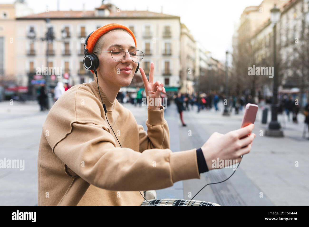 Junge Frau mit einem selfie beim Hören von Musik und Frieden Geste mit der Hand Stockfoto