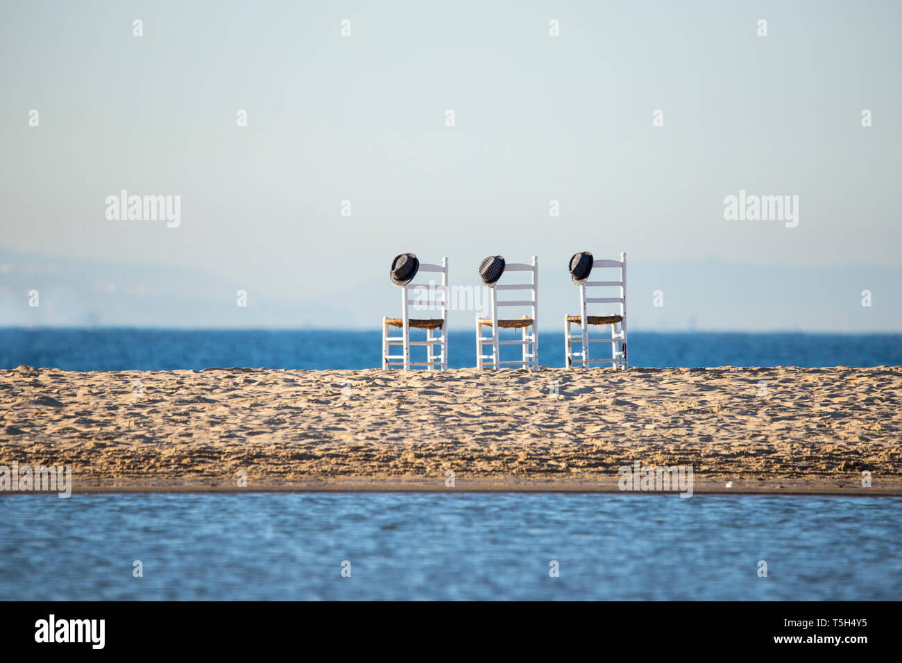 Drei leere Stühle mit Hüte Seite an Seite am Meer. Stockfoto