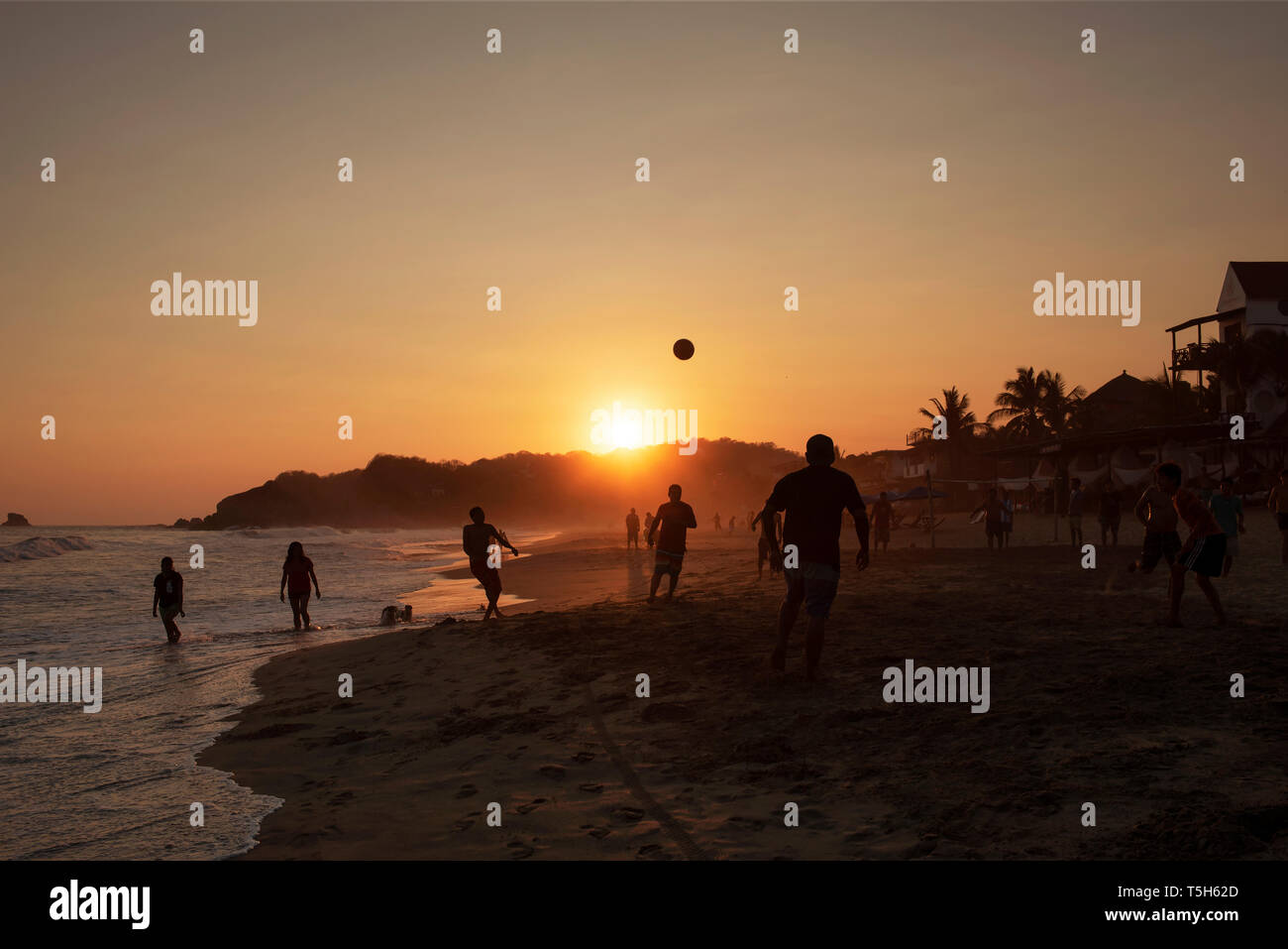 Silhouette von lokalen Männer Fußball spielen auf dem sandigen Strand von Zipolite. Oaxaca, Mexiko. Apr 2019 Stockfoto