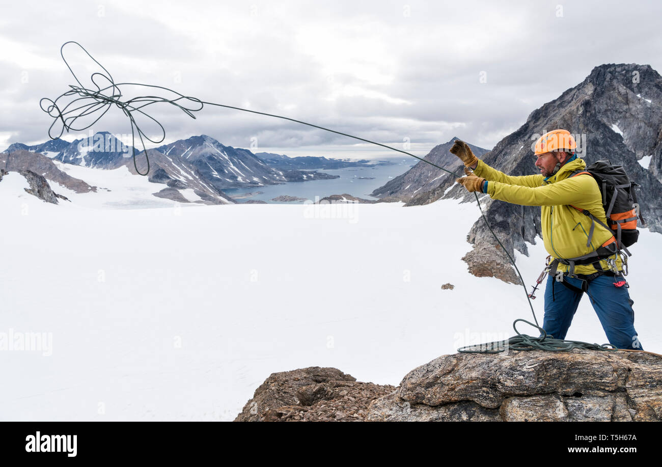 Grönland, Sermersooq, Kulusuk, Schweizerland Alpen, Bergsteiger auf dem Gipfel werfen Seil Stockfoto