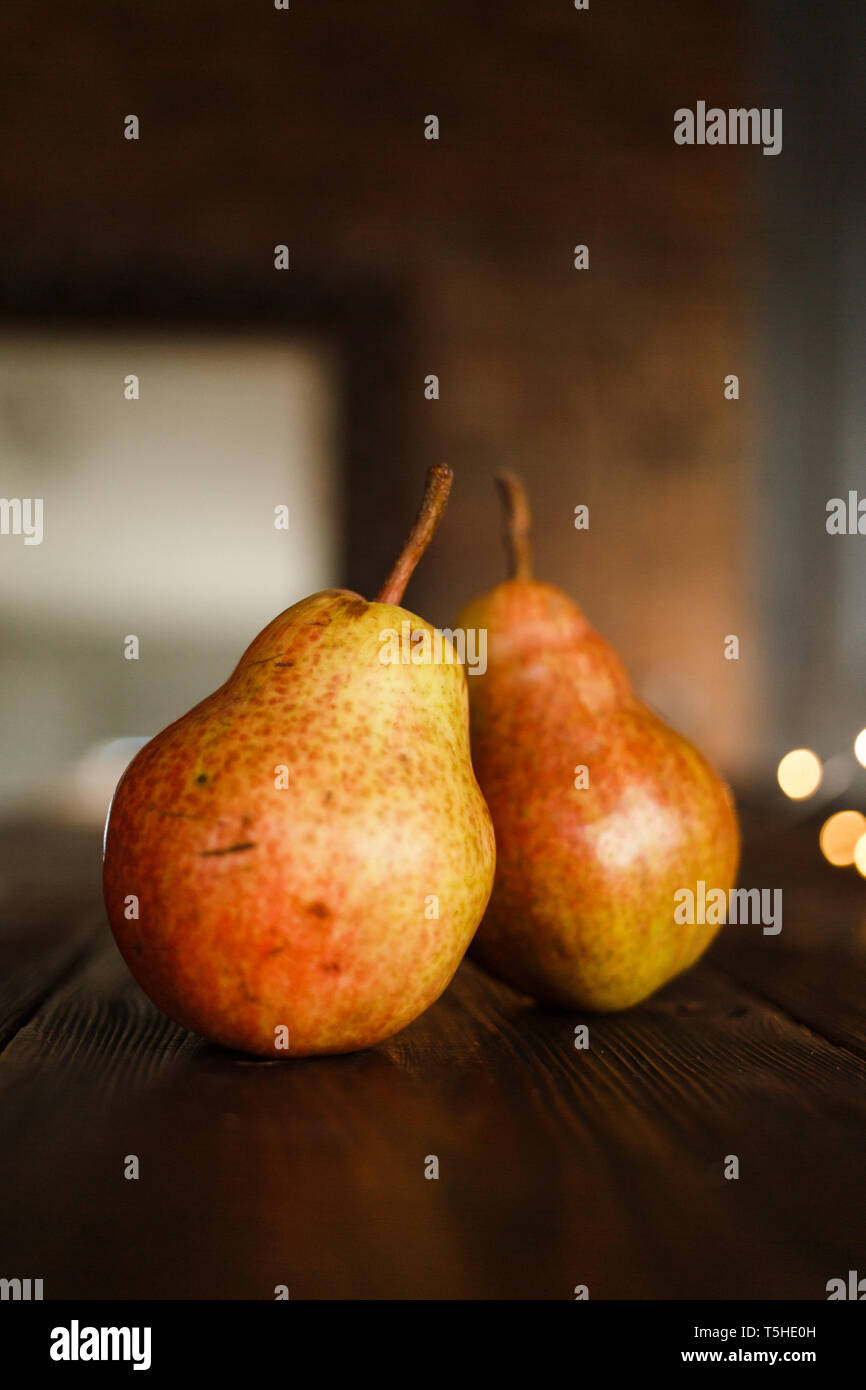 Schöne reife leckere Birnen auf einem großen Küche Holztisch mit einer Girlande der Lichter. Ein schöner Bildschirmschoner für einen Artikel über eine gesunde Ernährung, eine c Stockfoto