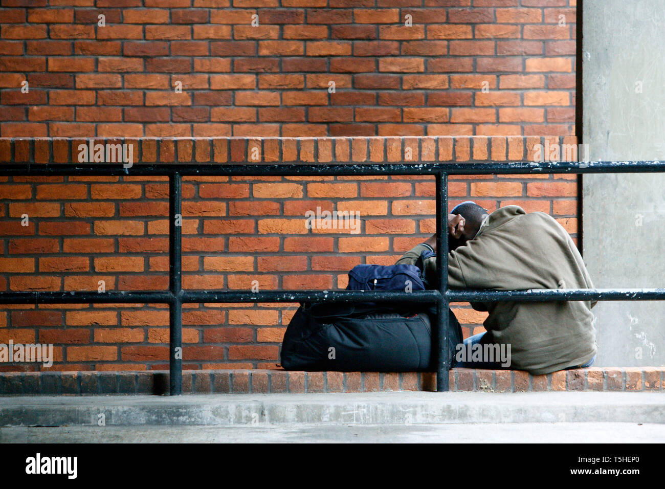 Ein Mann schlafen in einem Parkplatz auf seinem Beutel von gehört während des Tages. London. 25.08.2010. Stockfoto