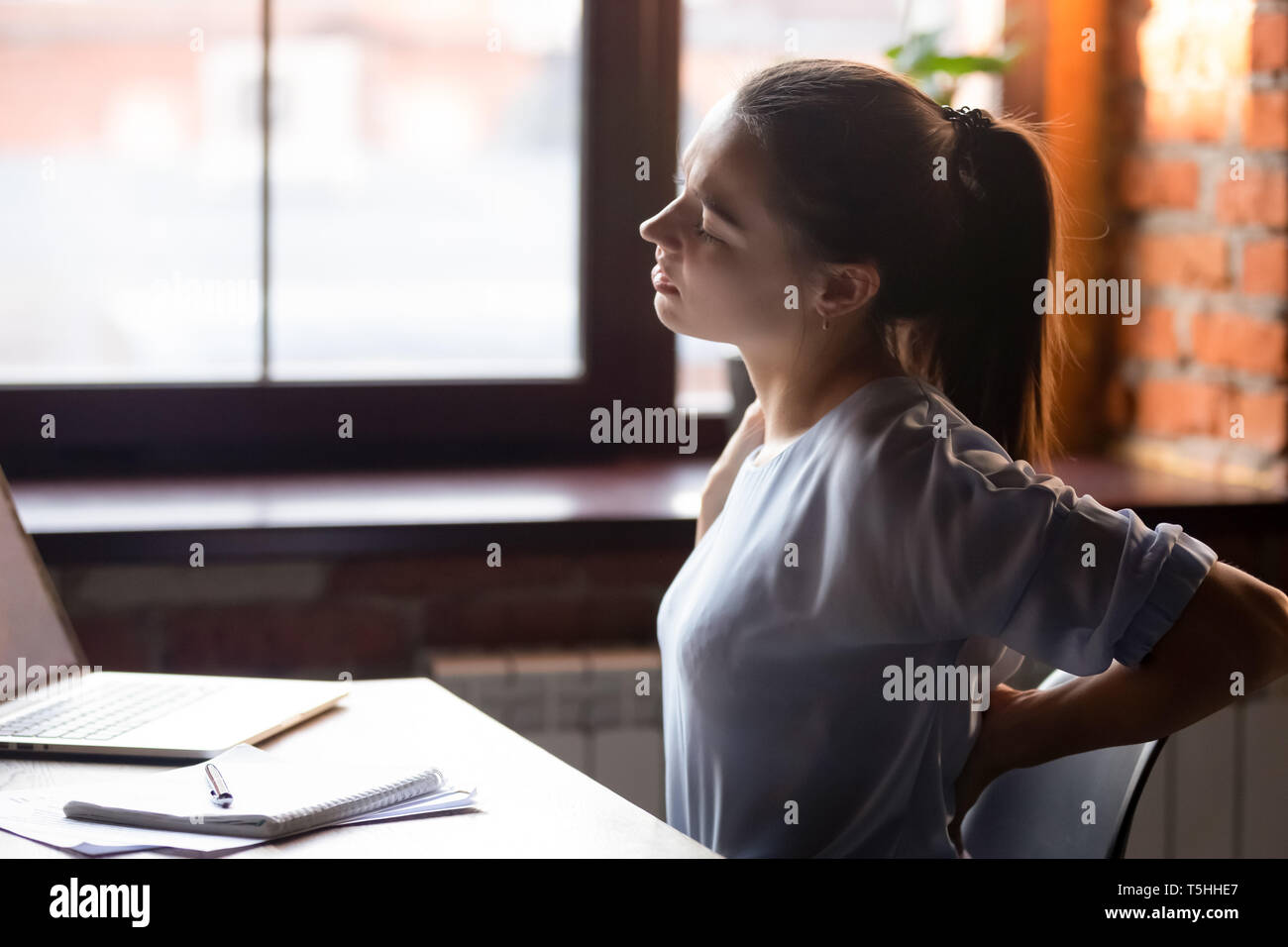 Frauen sitzen am Tisch sitzende Tätigkeiten Rückenschmerzen fühlt Stockfoto
