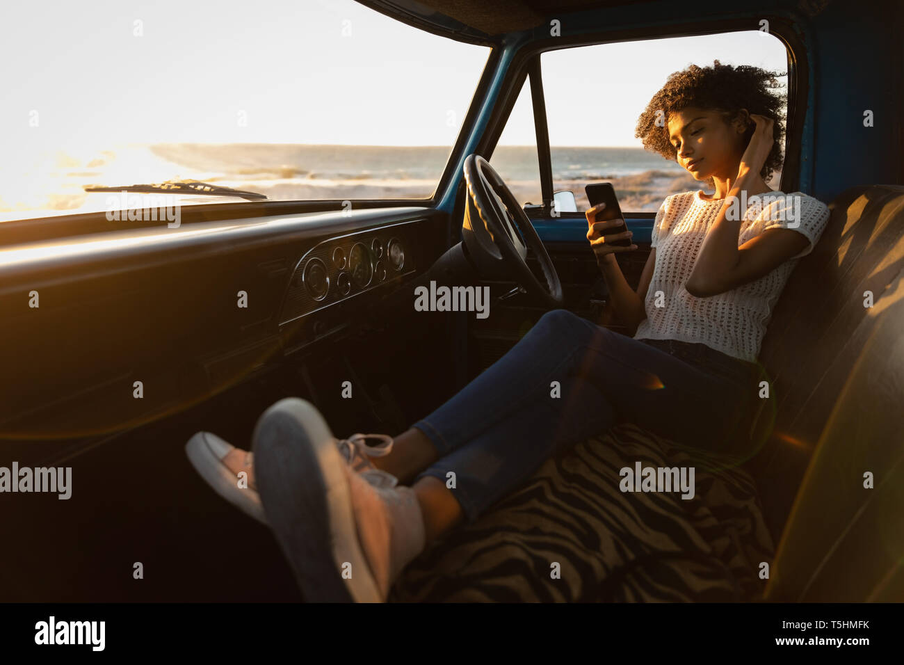 Schöne Frau mit Handy im Auto gelehnt Stockfoto