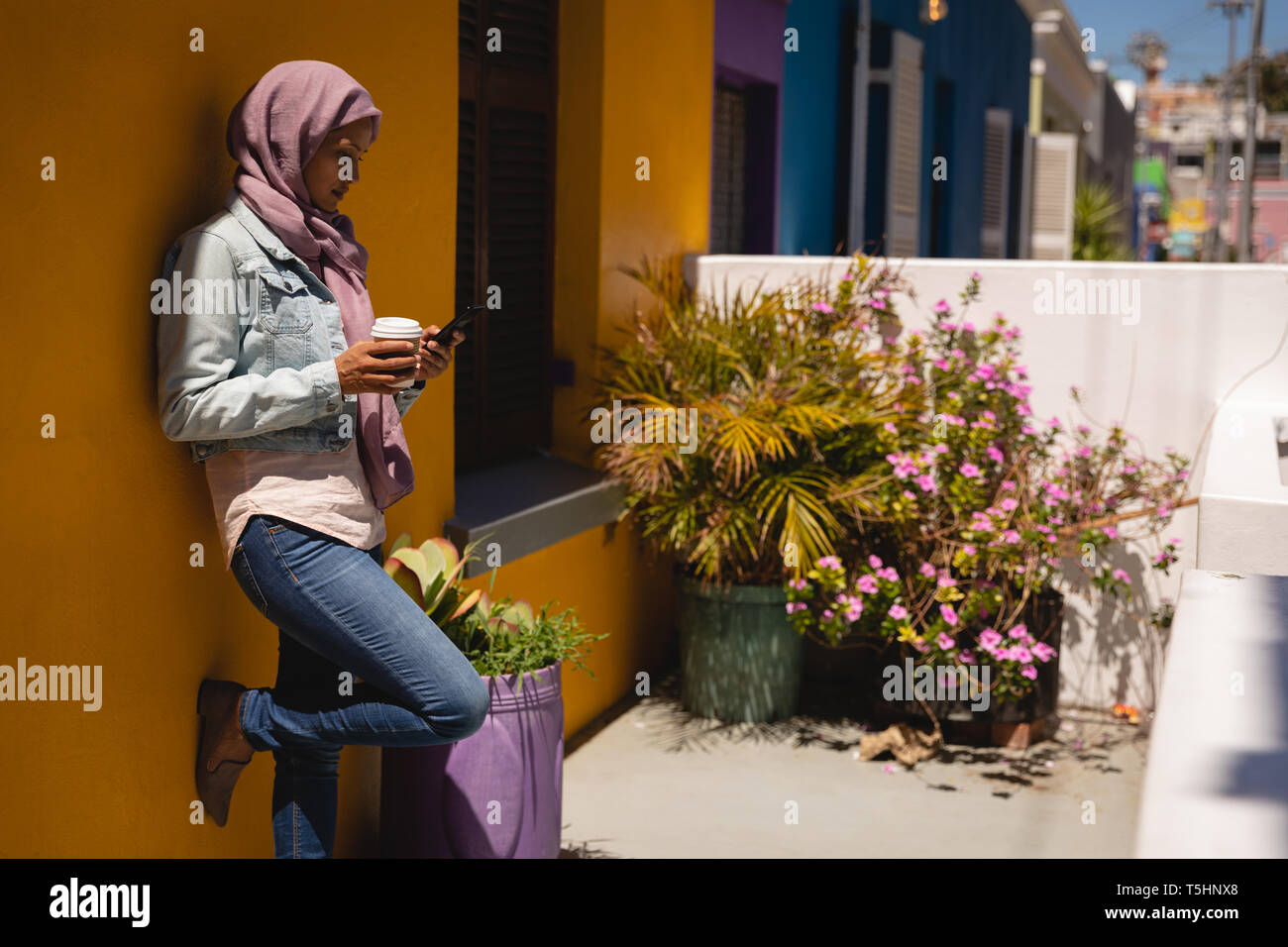Schöne Frau mit Handy während Kaffee im Haus Veranda in Stockfoto