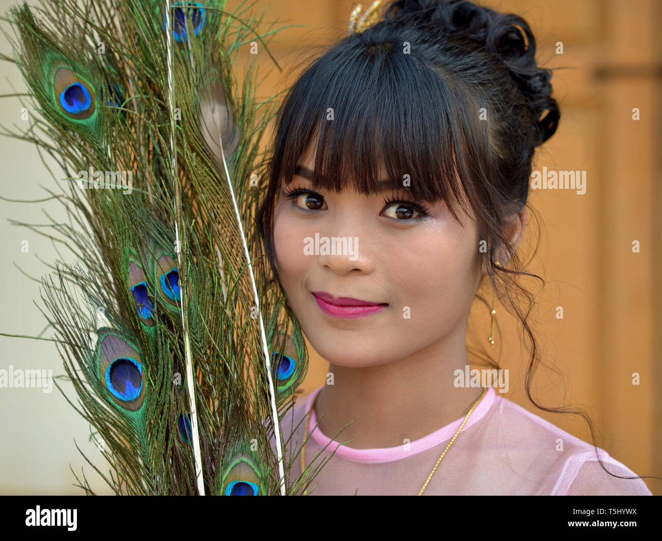 Schönen jungen burmesischen Frau mit Pfauenfedern posiert für die Kamera. Stockfoto