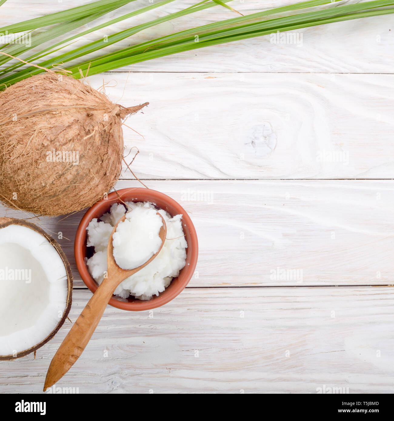 Flach Hintergrund der Kokosnuss, Kokosnussschalen, Öl in Ton Schüssel und Löffel auf weiße Holztisch Stockfoto