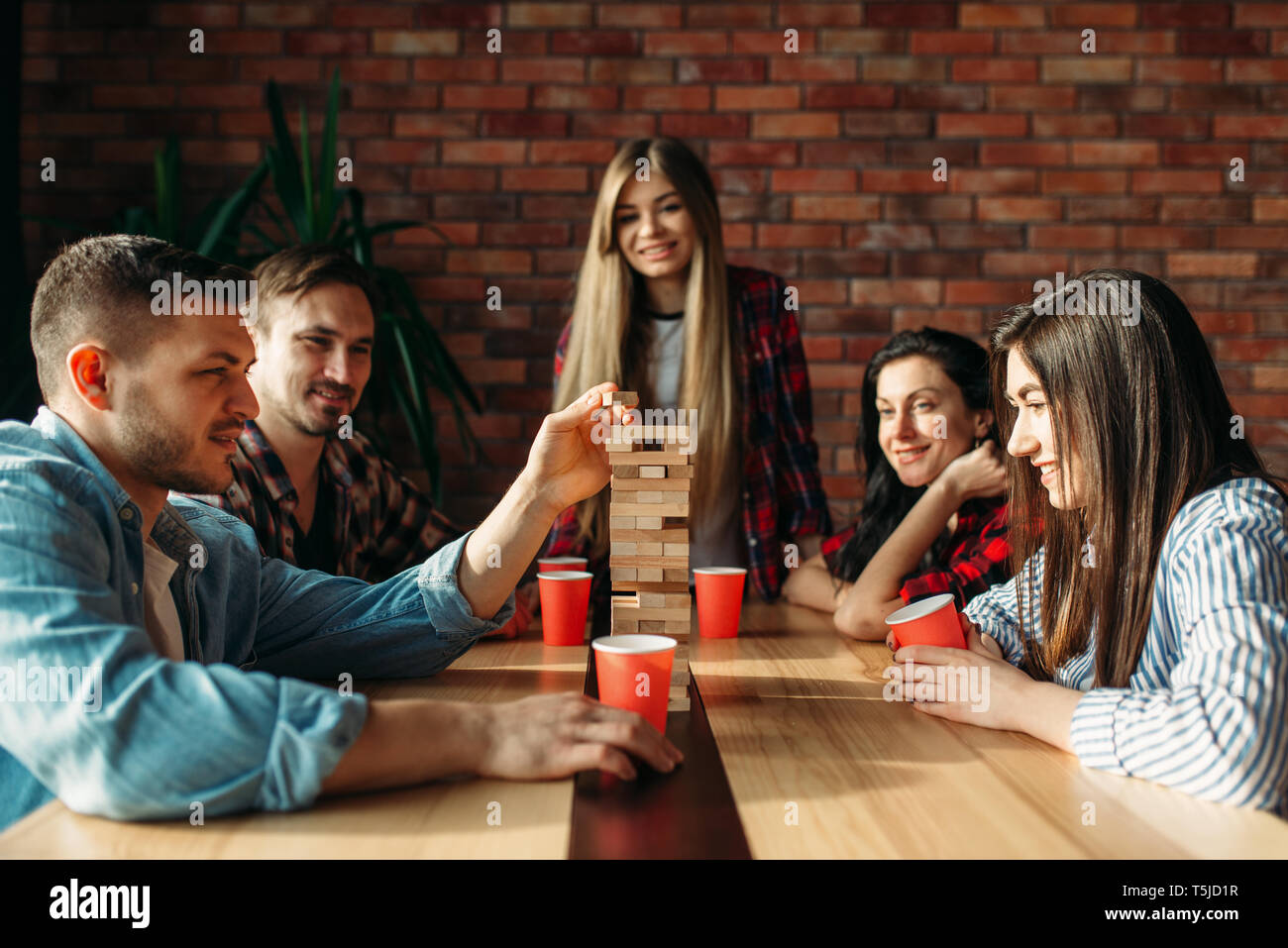 Lächelnd Freunde spielt Tabelle Spiel zu Hause, selektiver Fokus auf Turm. Brettspiel mit Holzklötzen, die hohe Konzentration, Unterhaltung für funn Stockfoto