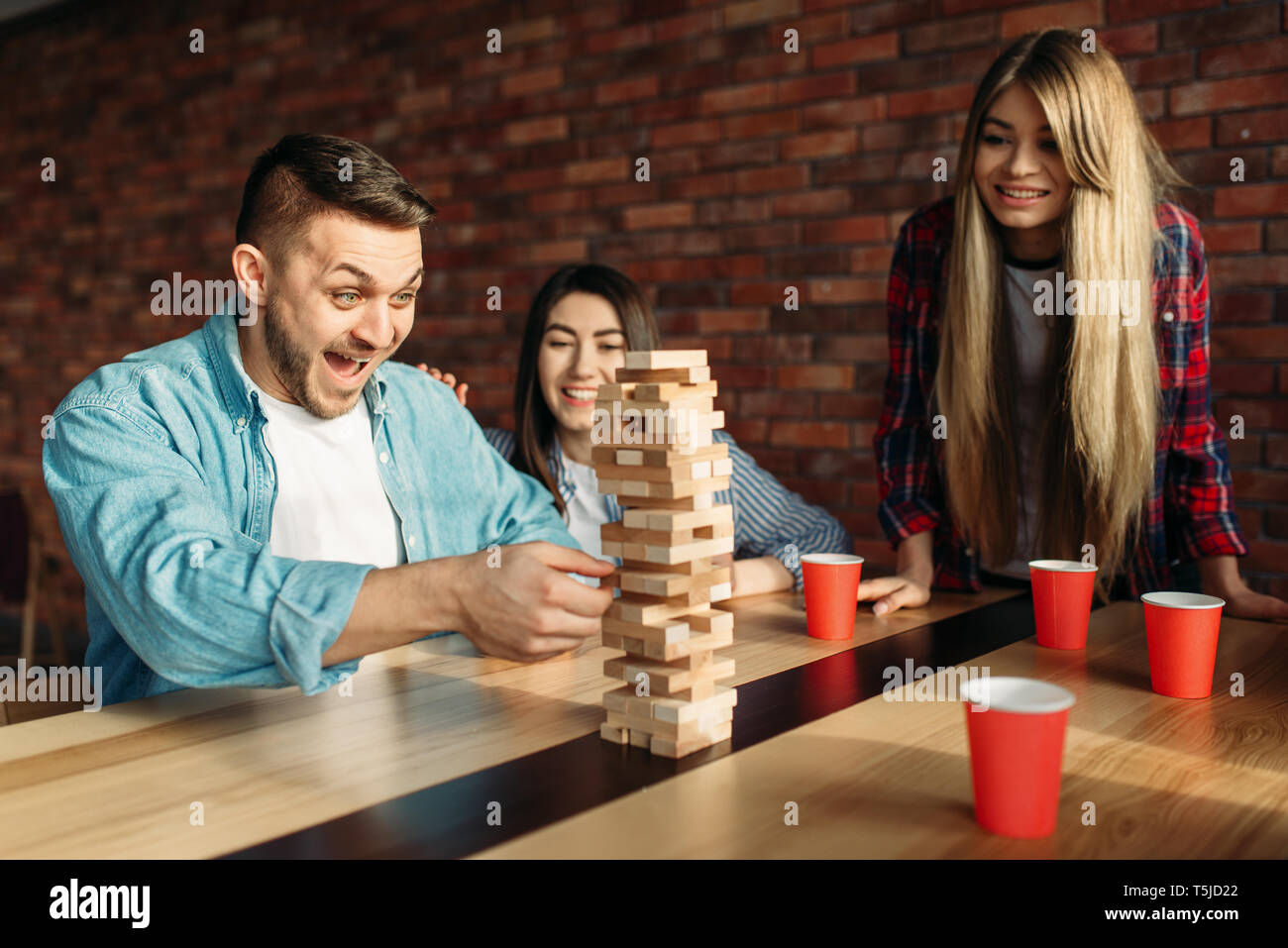 Lächelnd Freunde spielt Tabelle Spiel zu Hause, selektiver Fokus auf Turm. Brettspiel mit Holzklötzen, die hohe Konzentration, Unterhaltung für funn Stockfoto
