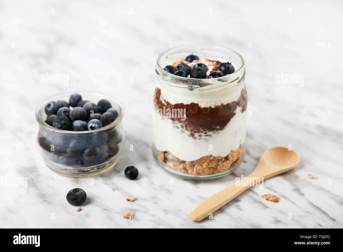 Jar von Chia pudding Parfait mit Schokolade und Joghurt mit Blaubeeren und Müsli Stockfoto
