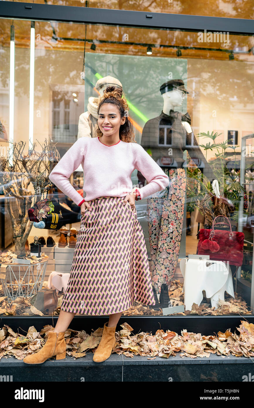 Junge Frau stand vor der Fashion Store, mit den Händen auf den Hüften Stockfoto